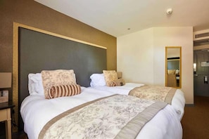Een hotelkamer met twee bedden, een grote spiegel en een klein bureau met een lamp.