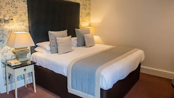 A neatly made bed with a dark headboard, two bedside lamps, and a small bedside table with a lamp and a telephone.