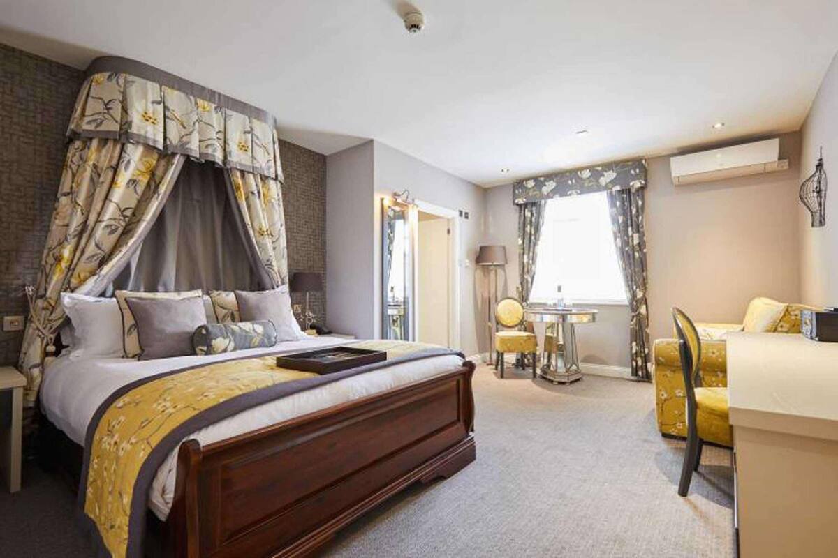 Een slaapkamer met hemelbed, bureau en stoel.