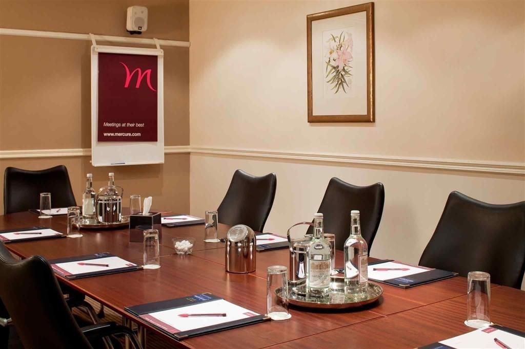 A conference room with a long table, chairs, and various items like bottles and a tray.