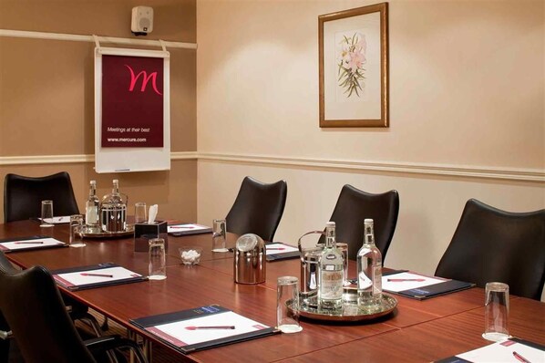 A conference room with a long table, chairs, and various items like bottles and a tray.