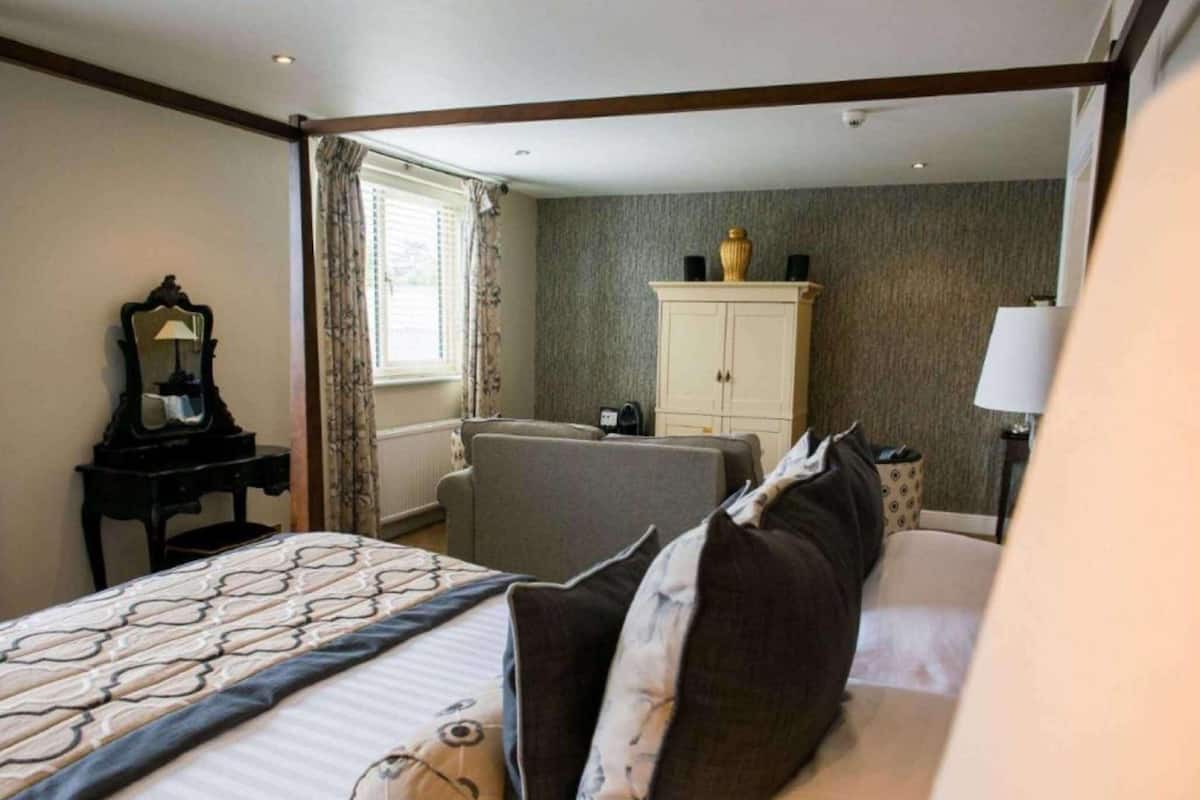 Een hotelkamer met een bed, een bureau met spiegel, een kledingkast en een raam met gordijnen.