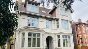 Ein zweistöckiges Haus mit Erkerfenster, einem Hauseingang mit Tür und einer kleinen Veranda mit Blumentöpfen.