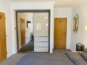 A hotel room with a sliding door leading to a hallway, a bed, a radiator, and a mirror on the wall. - Luxury Apartment-golden Triangle, Parking & Garden (Norwich)