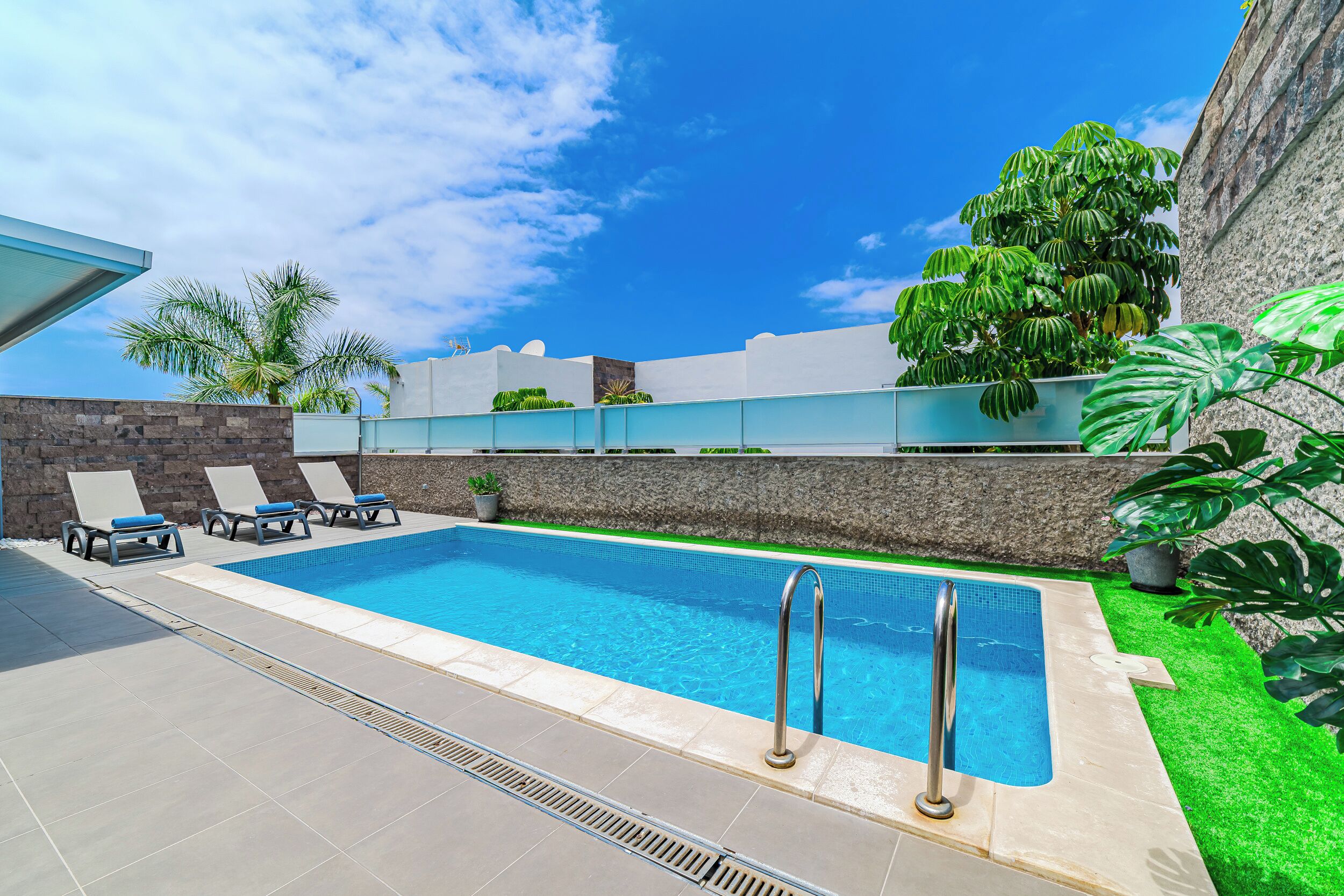 A swimming pool with lounge chairs and a stone wall.