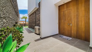 A modern building with a large wooden door, a stone wall, and a tiled floor.