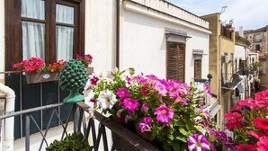 En balkon med blomsterkrukker og en pyntelig urne.
