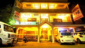 A multi-story building with a prominent entrance, a sign for "Park Inn WC CROWNS," and several parked vehicles. - JJS PARK INN (Chennai)