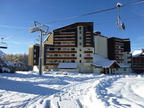A multi-story hotel with a ski lift in the background.