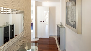 Un couloir moderne avec une table basse en verre, un vase décoratif et un miroir.