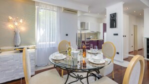 Un espace repas moderne avec une table en verre, des chaises blanches et un vase décoratif.