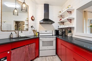 A kitchen with a red and white color scheme, stainless steel appliances, and a hanging light fixture.