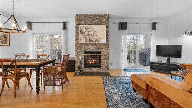 A living room with a fireplace, a dining area with wooden furniture, and a TV on a stand.