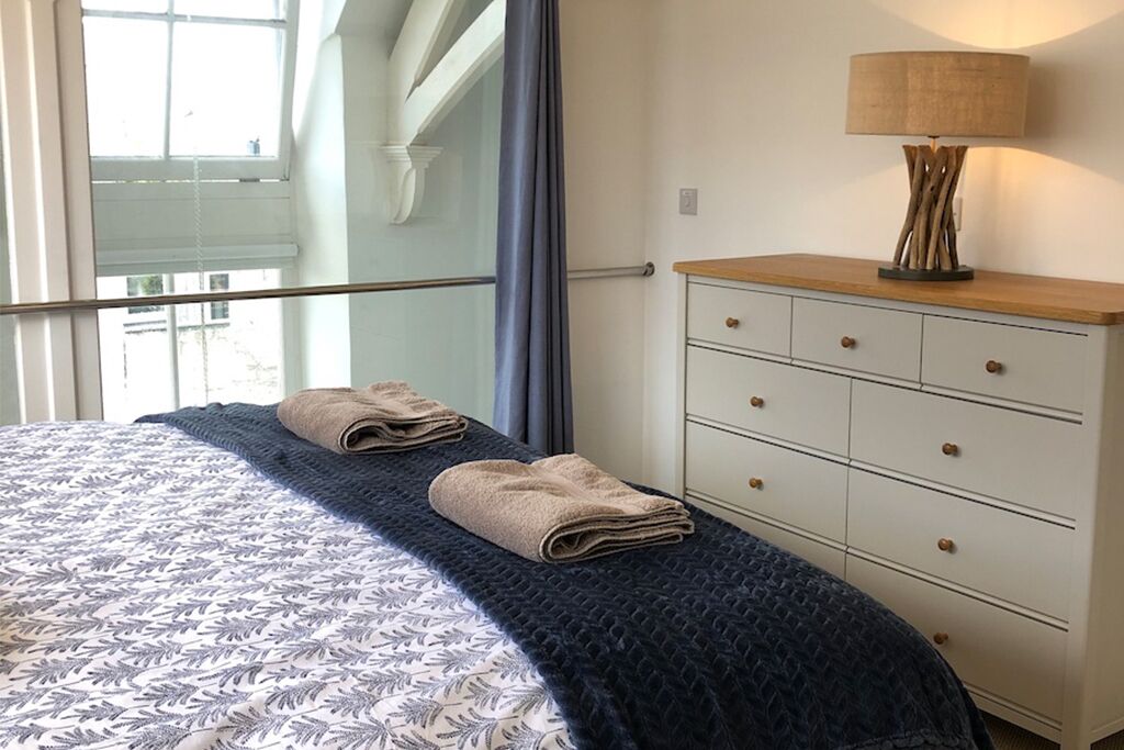 A bedroom with a bed, a dresser, and a lamp.