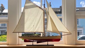 A model sailboat on a windowsill with a view of residential buildings. - Luxury duplex flat in central Falmouth with parking (Falmouth)