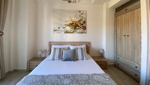 A bedroom with a large bed, two bedside tables with lamps, a wooden wardrobe, and a wall-mounted light fixture. - Villa Emerald - brand new house few minutes from the beach (Nikiti, Sithonia)