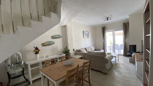 A spacious living area with a staircase, a dining table with chairs, a sofa, and a television. - Villa Emerald - brand new house few minutes from the beach (Nikiti, Sithonia)