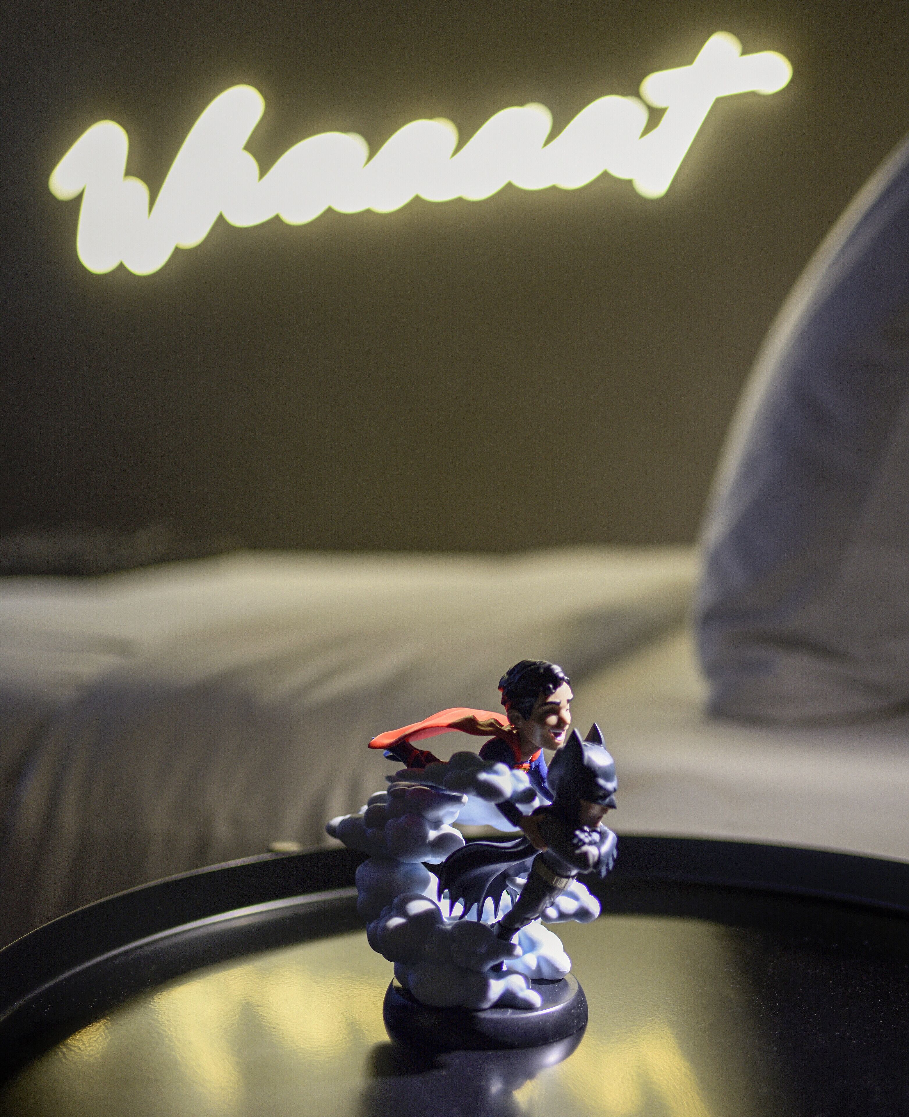 A figurine on a table with a neon sign in the background.