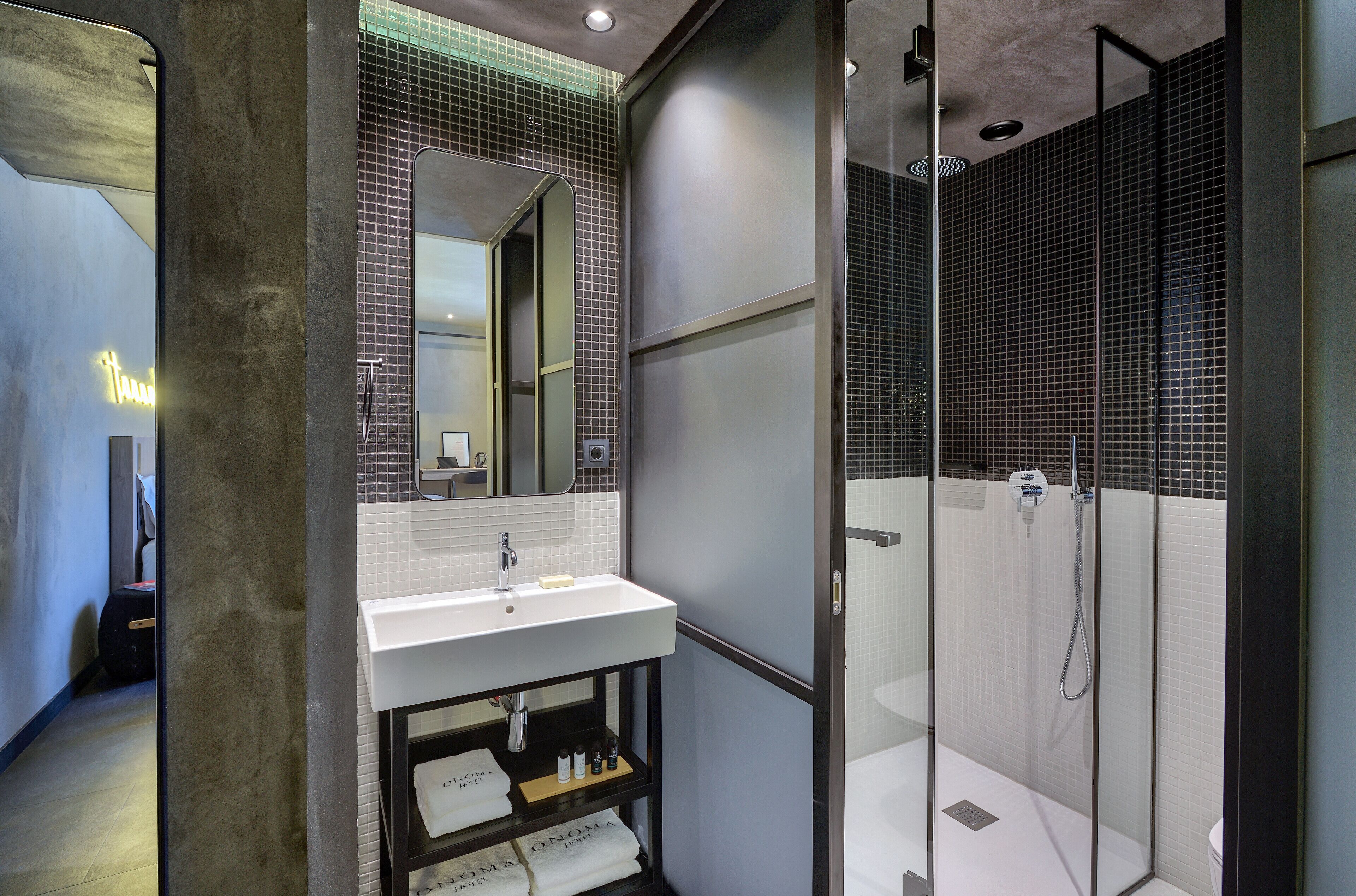 Een moderne badkamer met een douchecabine van glas, een wit wastafelmeubel en een spiegel erboven.