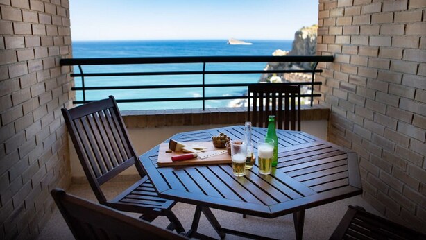 A balcony with a table set for two, featuring a bottle of beer, a glass, and a bowl of grapes. - Apartment Coblanca 16 (Benidorm)
