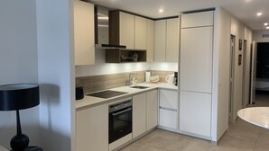 Une cuisine moderne avec des meubles blancs, un four encastré, un évier et un réfrigérateur.