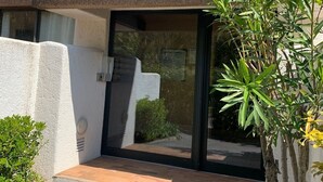 Un bâtiment moderne à l’extérieur blanc, doté d’un balcon avec une rambarde en métal et d’une porte avec un panneau de verre.