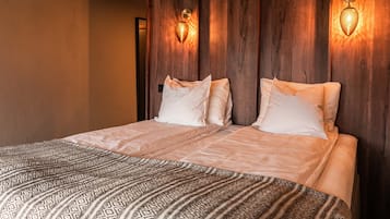 A double bed with patterned bedding, wooden headboard, and wall-mounted light fixtures.