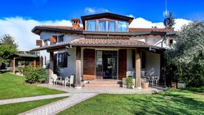 A two-story house with a tiled roof, a covered porch, and a well-maintained lawn.