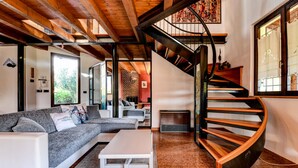 A modern living room with a curved staircase, a sectional sofa, and a white coffee table.