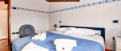 Una cama bien hecha con ropa de cama azul, almohadas blancas y toallas.