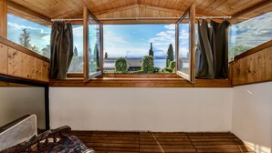 A wooden-paneled room with a large window offering a view of a lake and trees.