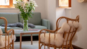 A room with a wicker chair, a small table, and a vase of flowers. - Hedera Estate, House Hedera VI (Dubrovnik)