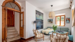 A spacious living room with a staircase, a green sofa, and a rattan chair. - Hedera Estate, House Hedera VI (Dubrovnik)