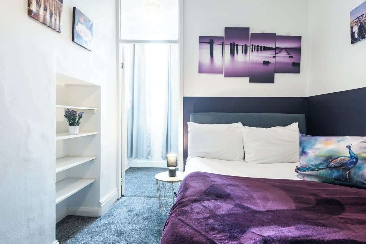 A bedroom with a bed, a headboard, a shelf unit, and a window.
