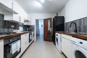 A modern kitchen with a stove, oven, microwave, and washing machine. - Hull Largest 6 Bedrooms House - Sleeps 13 (Hull)