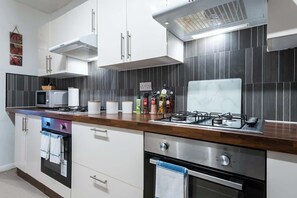 A modern kitchen with white cabinets, a gas stove, a microwave, and a built-in oven. - Hull Largest 6 Bedrooms House - Sleeps 13 (Hull)
