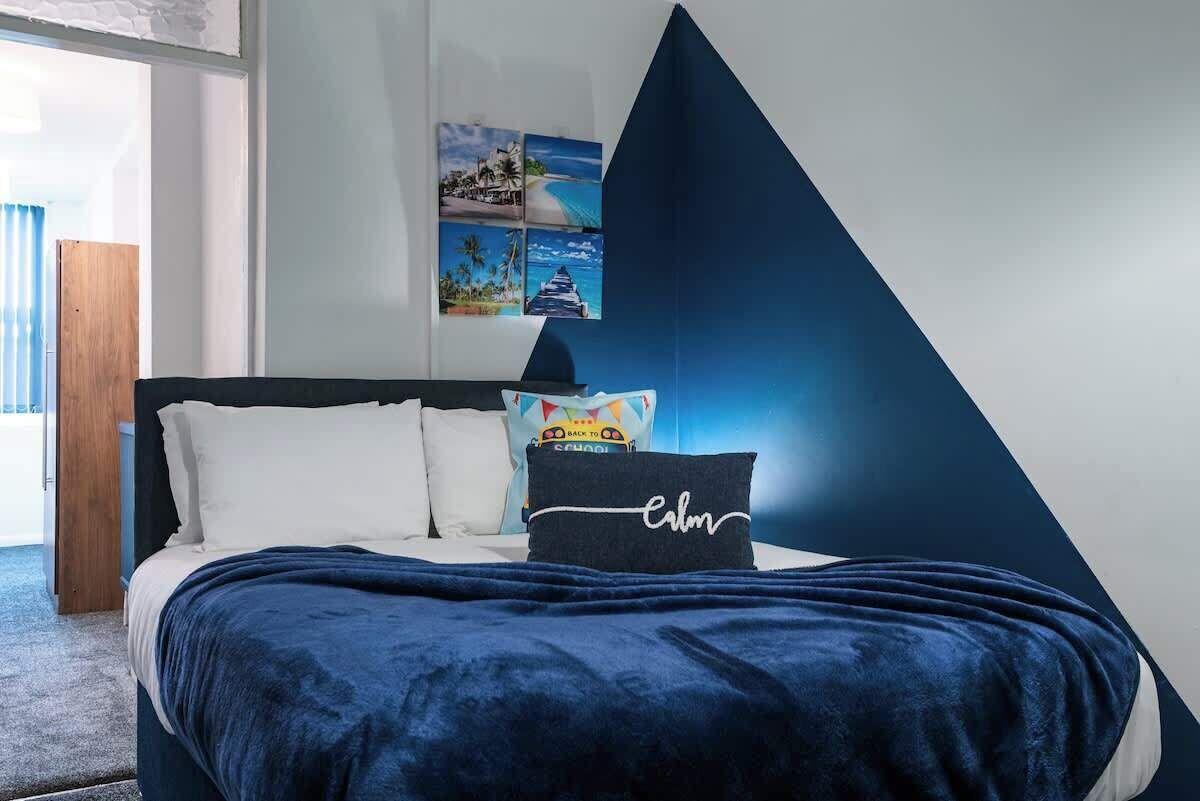 Een slaapkamer met een bed, kussens en een muur met een geometrisch ontwerp.