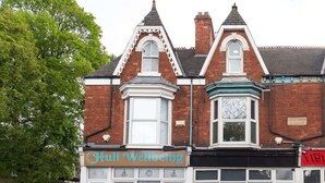 Um edifício tradicional com uma placa indicando 'Hull Wellbeing' e uma fachada visível.