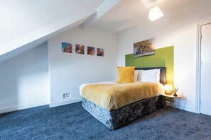 A bedroom with a bed, a nightstand, a lamp, and wall art. - Hull Largest 6 Bedrooms House - Sleeps 13 (Hull)