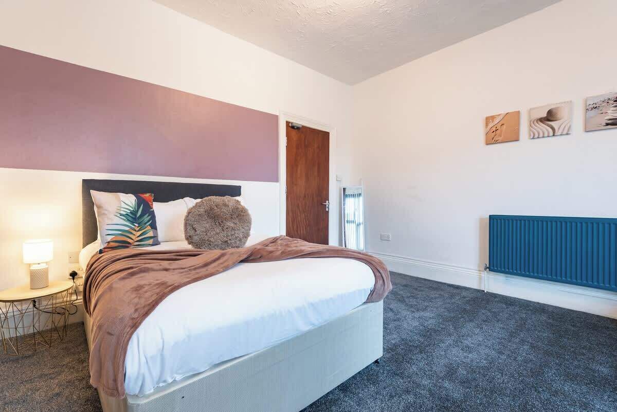 Ein Schlafzimmer mit Bett, Nachttisch, Lampe und Kunstwerk an der Wand.