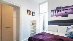 Quarto com cama, guarda-roupa, estante e janela.