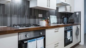 Uma cozinha moderna com fogão a gás, forno e micro-ondas. Há armários e bancada.