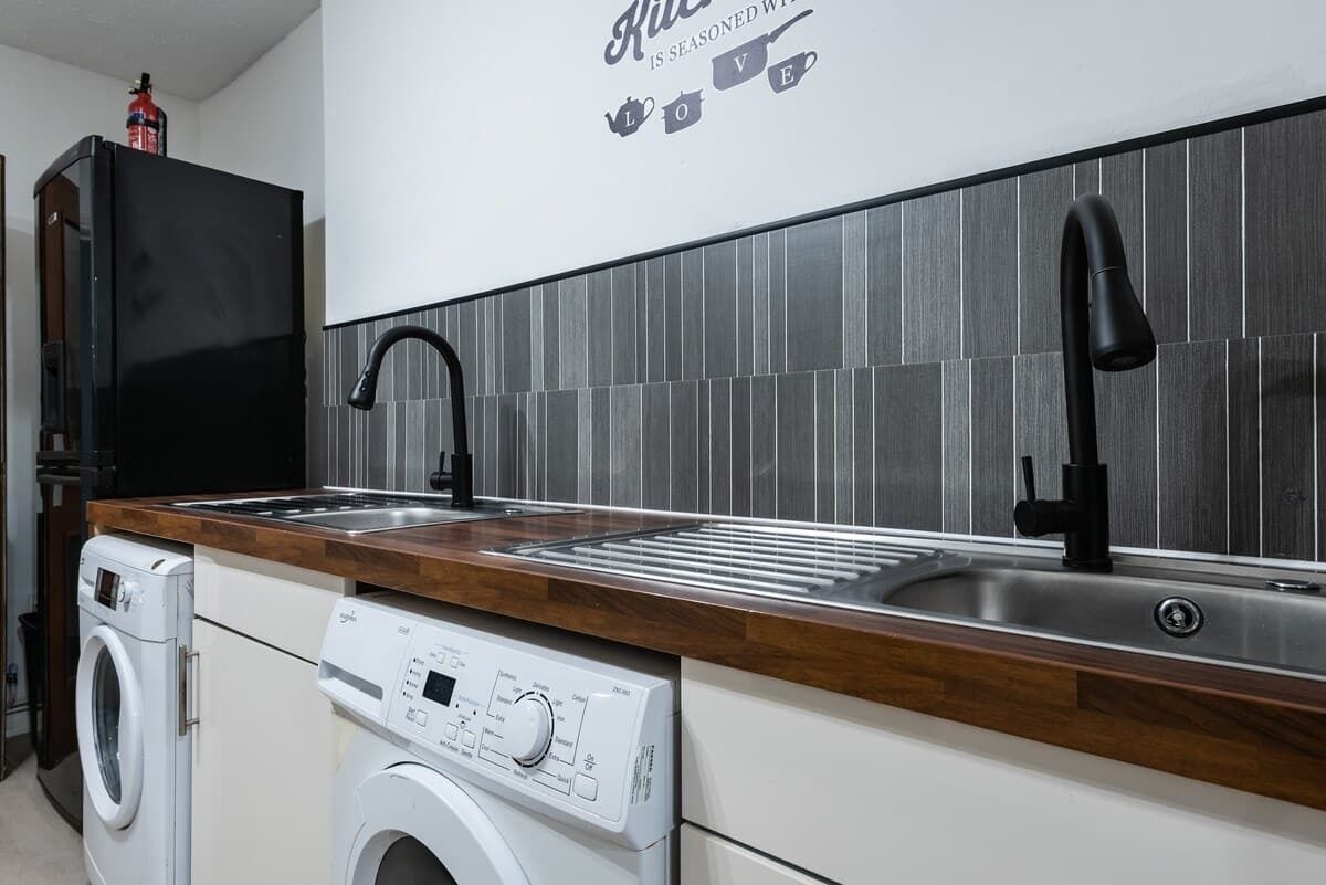 A modern kitchen with a stainless steel sink, a built-in washing machine, and a black faucet.