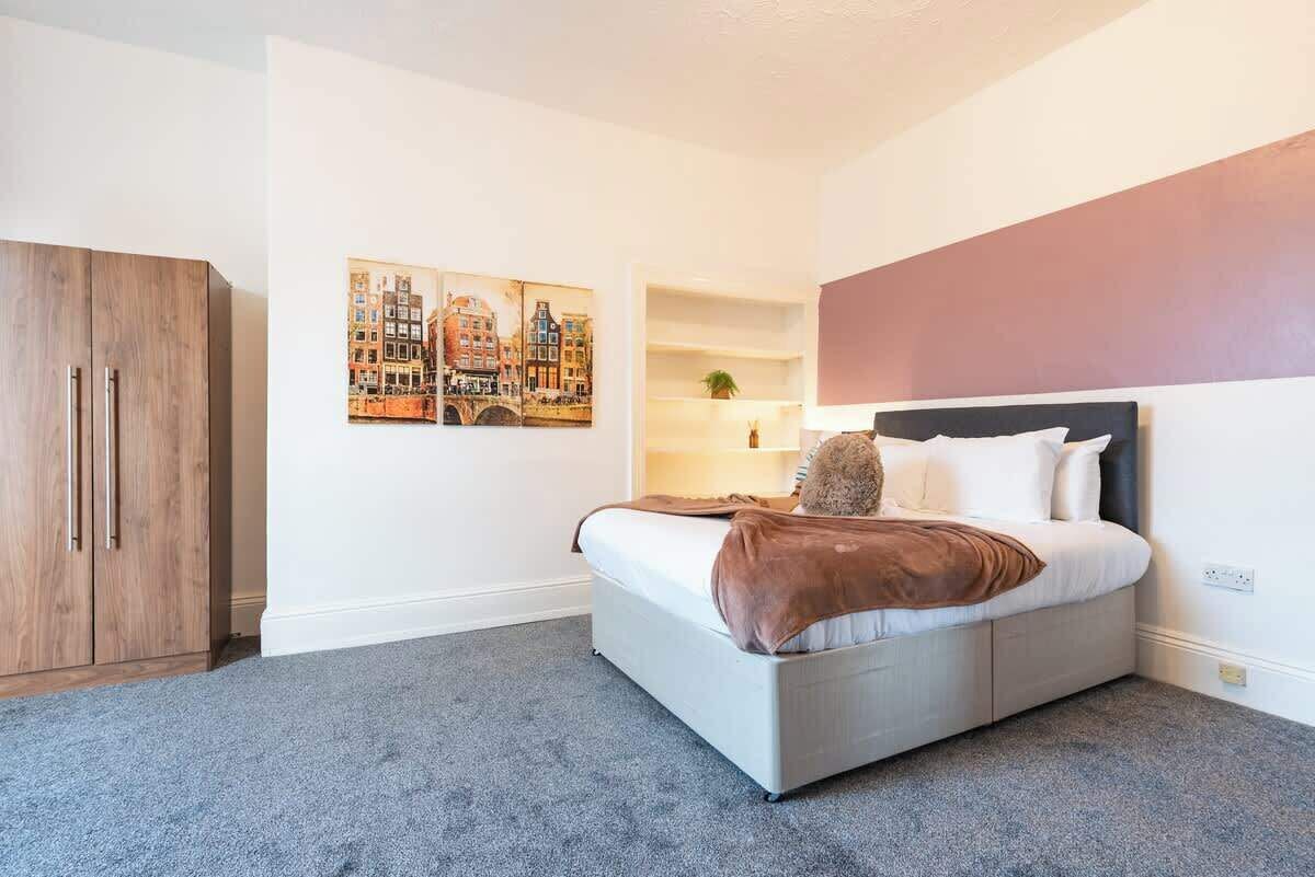 Ein Schlafzimmer mit einem Bett, einem Kleiderschrank, einer Regalwand und einem Bild an der Wand.