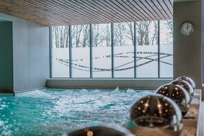 An indoor swimming pool with a view of a snowy landscape through large windows. - Ensana Ursina (Sovata)