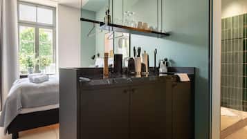 Un baño moderno con tocador negro, un espejo grande y repisas con artículos de aseo.