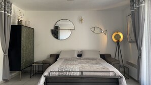 Quarto moderno com cama, mesas de cabeceira, penteadeira, espelho e abajur.