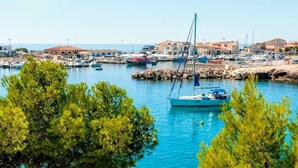 Marina com barcos atracados, rodeada por edifícios e árvores.