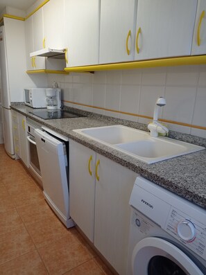 A kitchen with white cabinets, a microwave, a coffee maker, a dishwasher, and a washing machine.