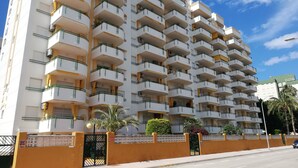 A multi-story residential building with balconies, a gated entrance, and a clear sky. - CANCUN VII 6º,  Solo Familias! (Playa de Gandía)